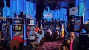 Een casino met meerdere gokkasten en een bord met de tekst Remington Park Casino.