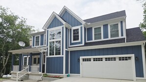 A two-story house with a garage, a covered porch, and a satellite dish.