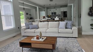 A modern living room with a large white sectional sofa, a wooden coffee table, and a patterned rug.