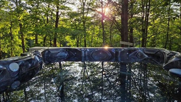 A hot tub surrounded by trees with sunlight filtering through.