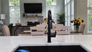 A modern kitchen with a large island, a built-in oven, and a flat-screen TV above the counter.