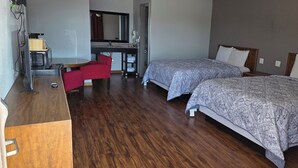 A hotel room with two beds, a desk with a chair, a mirror, and a microwave.