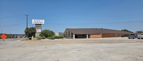 A building with a sign reading 'GATE 1' and a parking lot with several vehicles.