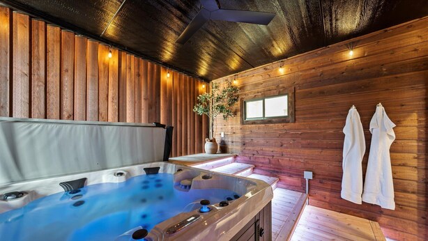 A wooden cabin interior with a hot tub, wooden walls, and a window.