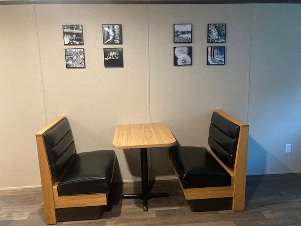 A small seating area with two black leather booths and a wooden table.