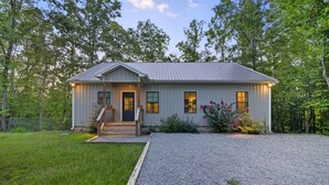 A single-story house with a front porch, a gravel driveway, and a well-maintained lawn.