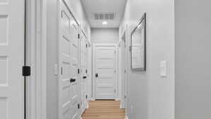 A hallway with white doors and wooden flooring.