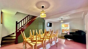 Amplia sala de estar con escaleras, una mesa de comedor con sillas, un televisor y un sofá.