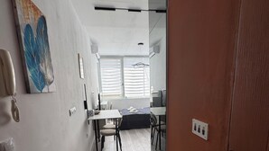 Una camera moderna con zona pranzo, un quadro appeso al muro e una porta in legno.