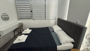 Una camera da letto con un letto, una scrivania e una finestra con tende.