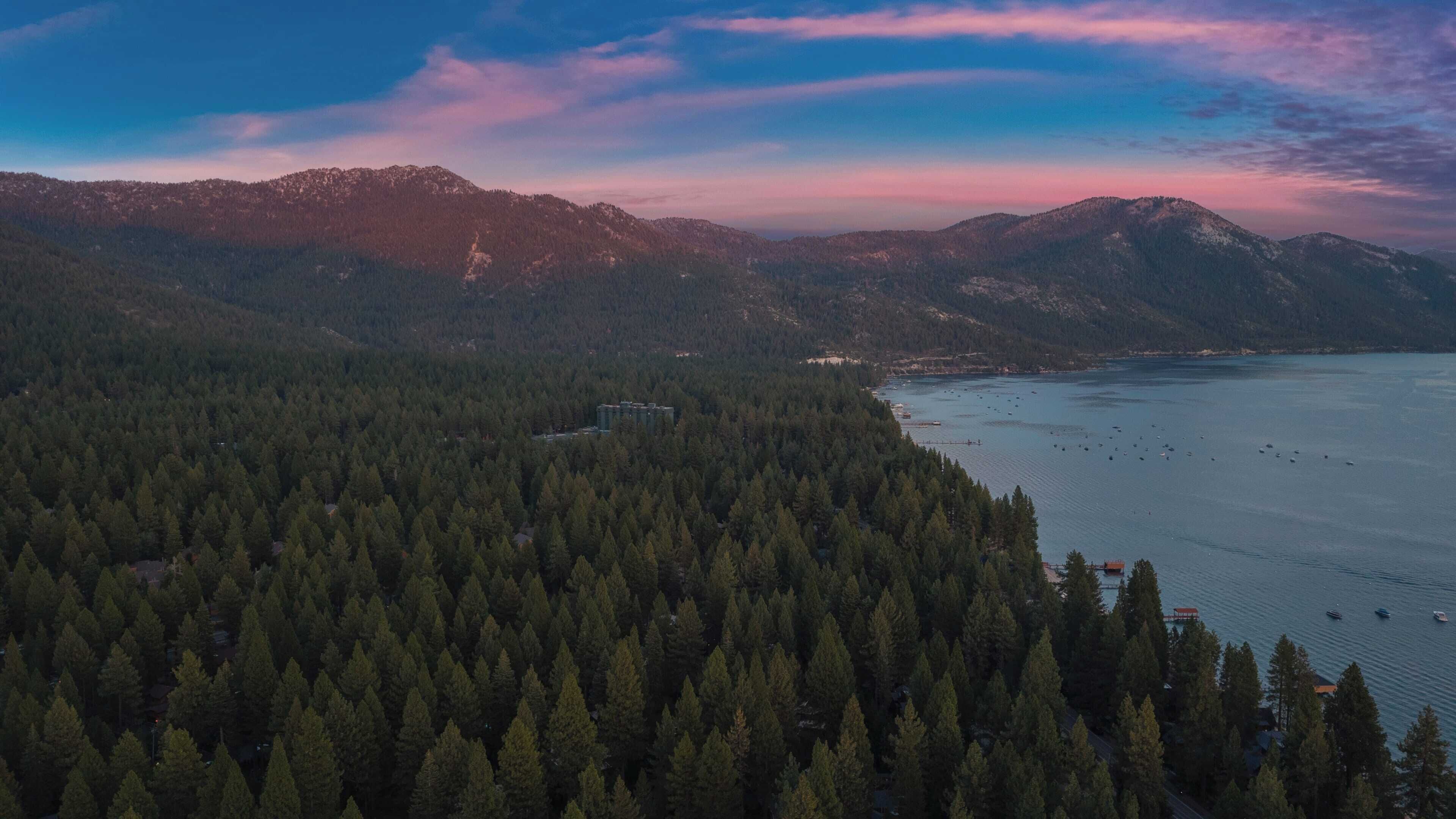 A mountainous landscape with dense forests and a body of water.