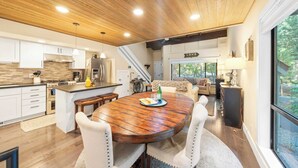 A modern kitchen with a wooden ceiling, white cabinets, and a dining area with a large wooden table and four chairs. - Near Ski, Beach, & Hiking Trails + Clubhouse Pool & Hot Tub Access Juanita Blue by Avantstay (Incline Village)