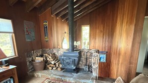 Interior acogedor de una cabaña con chimenea de piedra, paredes de madera, un sofá y una mesita de centro.
