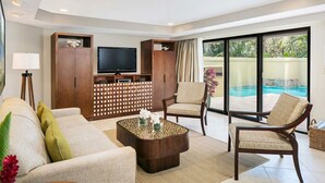 Amplio salón con sofá, dos sillones, una mesa de centro, televisor y vista a la piscina.