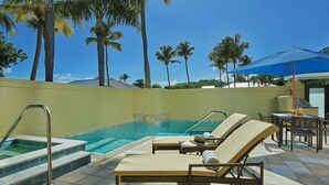 Un área de piscina con sillas de descanso, una mesa y una sombrilla azul.