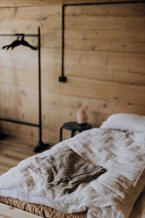 Une pièce en bois avec un lit, un luminaire suspendu et une petite table.