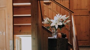 A wooden staircase with a vase of white flowers on a wooden ledge.