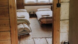 A wooden cabin with two beds, a bench, and a small table.