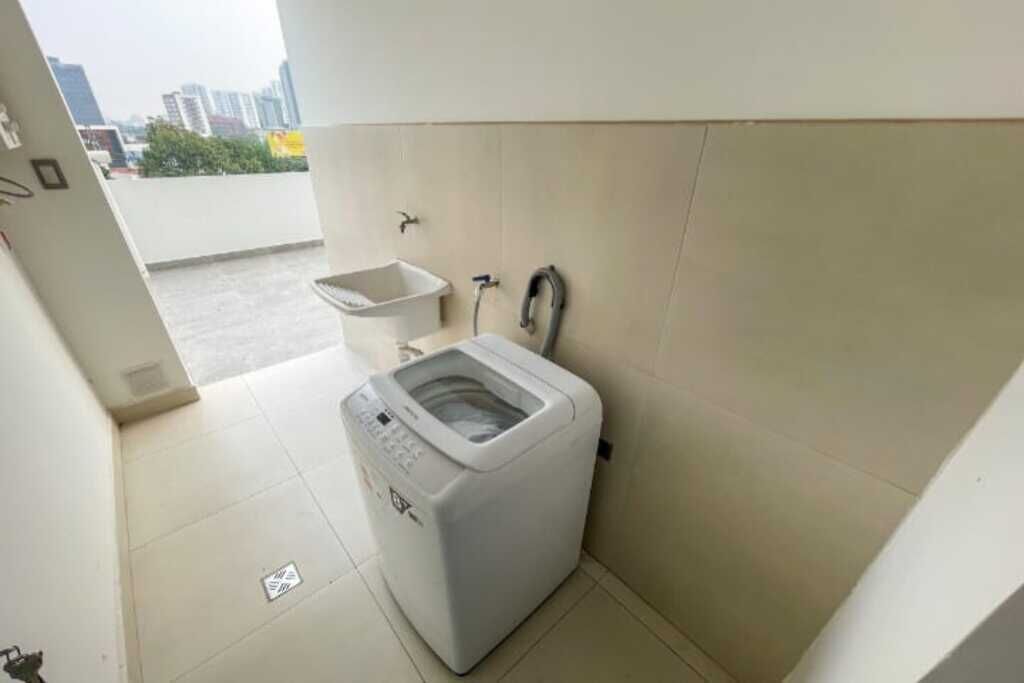 A small laundry room with a washing machine, a sink, and a faucet.