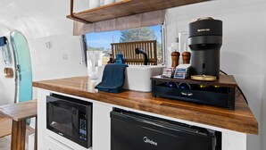 A compact kitchenette with a microwave, coffee maker, and storage cabinets. - Starlight Streamer - Cozy Airstream Escape in Williams, AZ (Williams)