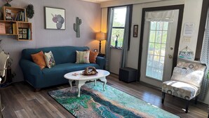 Ein gemütliches Wohnzimmer mit einem blauen Sofa, einem weißen Couchtisch und einem gemusterten Teppich.