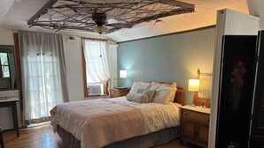 Ein Schlafzimmer mit Bett, Nachttischen, einer Lampe und einem Deckenventilator.