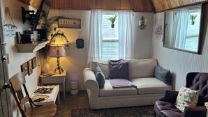 A cozy living room with a sofa, a chair, a lamp, and a small table. - 1 Bedroom Vacation Cottage in San Marcos/Wimberley, TX (San Marcos)