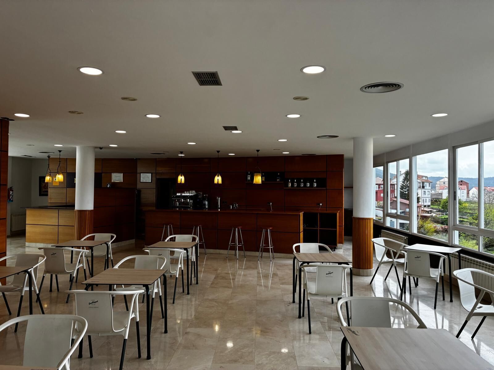 Ein modernes Restaurant mit Bar, großen Fenstern und Blick auf die Stadt.