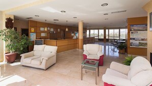 A hotel lobby with a reception desk, seating area, and a view of the outdoors. - My Rooms City Hotel Monte Blanco (Neaño)