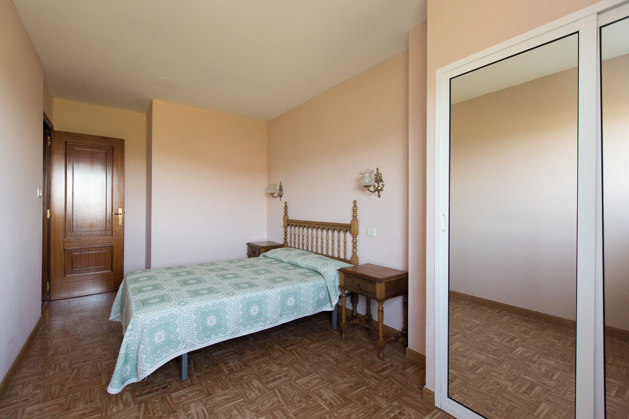 A bedroom with a wooden bed, two bedside tables, and a wardrobe.