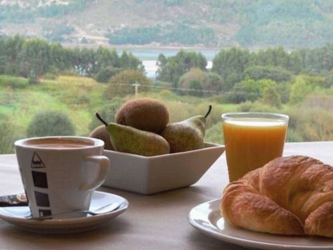 A table with a croissant, a glass of orange juice, and a bowl of fruit.