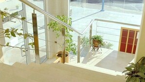 A modern interior with a glass staircase, indoor plants, and a view of the street outside. - My Rooms City Hotel Monte Blanco (Neaño)