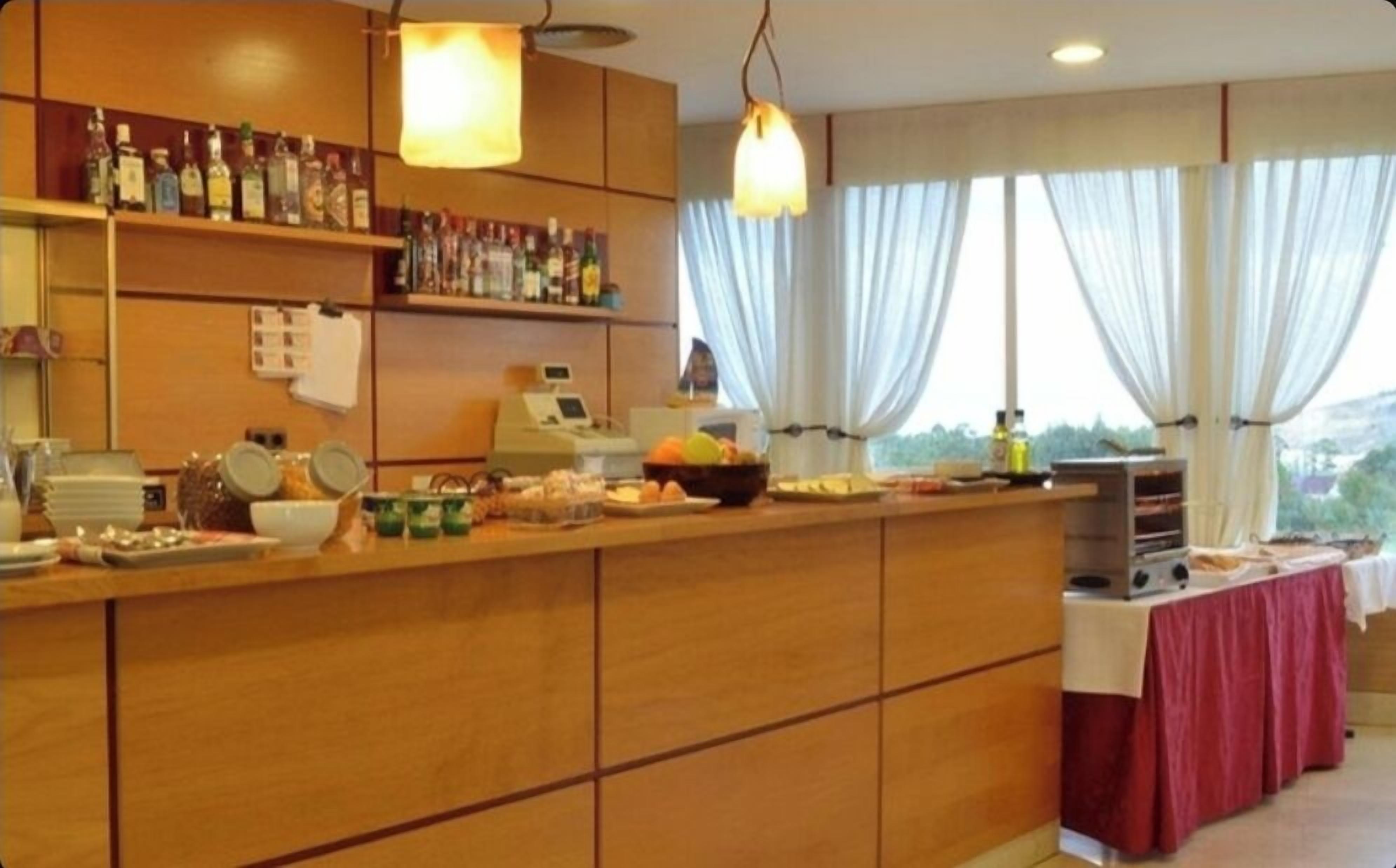 A buffet setup with a variety of food items and beverages, a cash register, and a view of the outdoors through large windows.