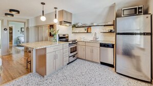 A modern kitchen with a central island, stainless steel appliances, and pendant lighting. - BozemanGetaways - Charming Condo Steps to Main (Bozeman)