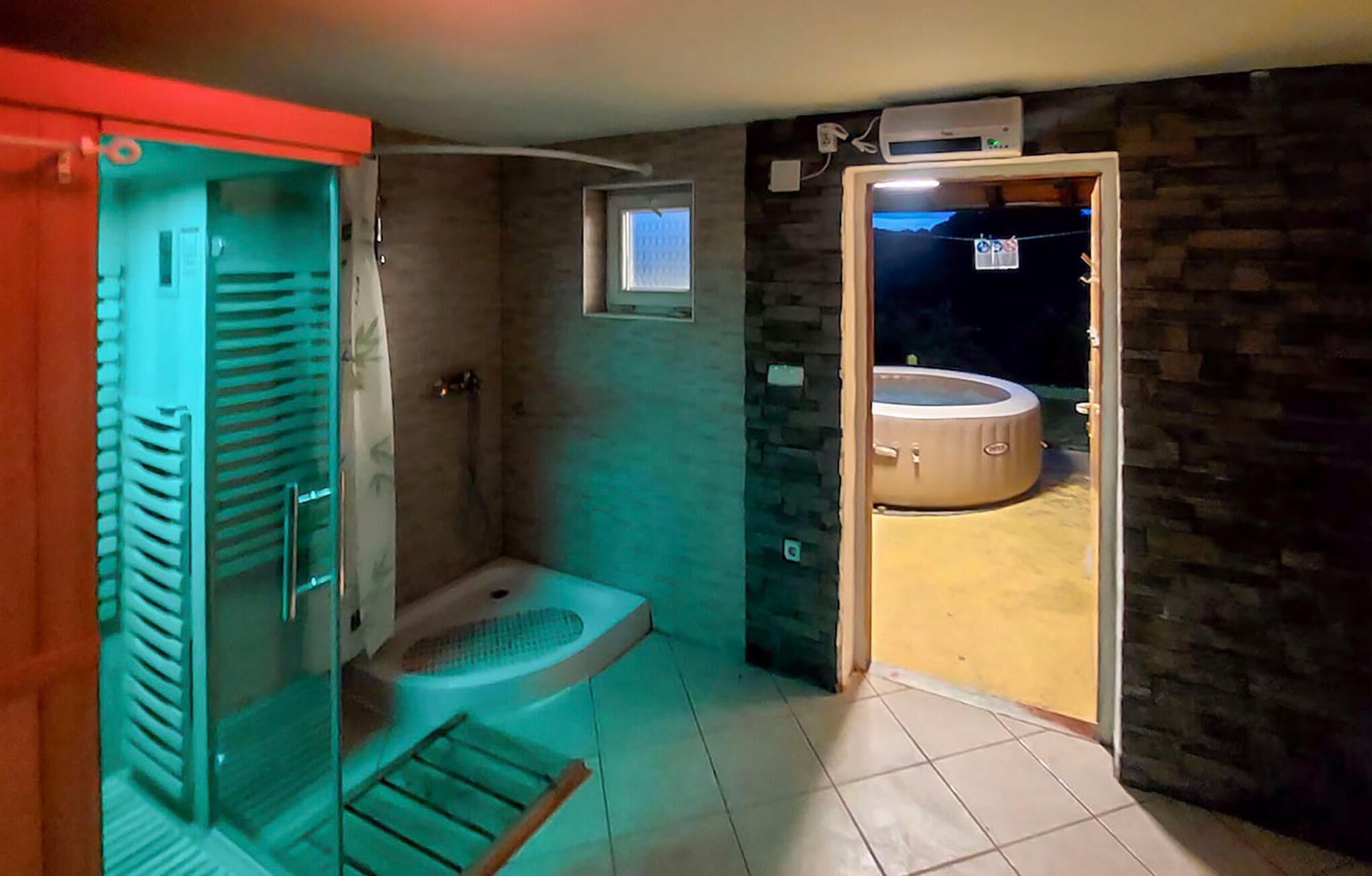 Un baño con ducha, inodoro y un ventanal pequeño.