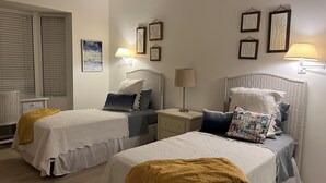 Ein Schlafzimmer mit zwei Betten, jeweils mit Kopfteil, Nachttischen, Lampen und Wanddekoration.