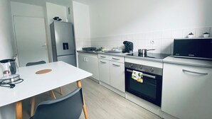Eine moderne Küche mit weißen Schränken, einem Backofen, einer Mikrowelle und einer Kaffeemaschine.