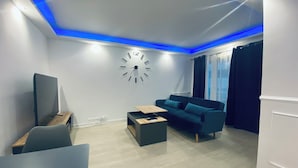 Ein modernes Wohnzimmer mit einer Couch, einem Couchtisch, einem Fernseher und einer Wanduhr.