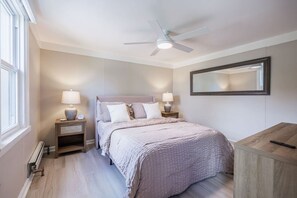 A bedroom with a bed, nightstands, a ceiling fan, a mirror, and a wooden dresser.