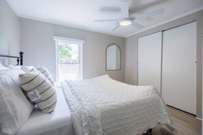 Un dormitorio con cama, ventana, ventilador de techo y armario.