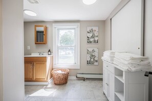 Un baño moderno con tocador de madera, un ventanal grande y un perchero blanco.