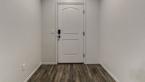 A hallway with a white door, a light switch, and a thermostat on the wall. - Walk to Downtown Edmond! Pet Friendly, Garage Access, King Bed! (Edmond)