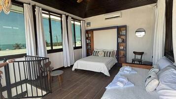 Une chambre à coucher comprenant un lit, un bureau, une chaise, une bibliothèque et un balcon avec une balustrade.