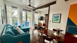 Ein modernes Wohnzimmer mit einer Couch, einem Esstisch und einem Deckenventilator.