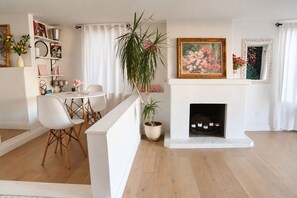 A living room with a fireplace, a dining area, and a potted plant.
