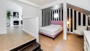 A modern bedroom with a bed, a nightstand, a chair, and a wall-mounted lamp. - Stunning 1-bedroom apartment with view (Glendale)