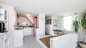 A modern kitchen with white cabinetry, a black and white patterned floor, a pink refrigerator, and a dining area with a table and chairs. - Stunning 1-bedroom apartment with view (Glendale)