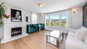 A modern living room with a fireplace, a sofa, a coffee table, and a view of the city. - Stunning 1-bedroom apartment with view (Glendale)