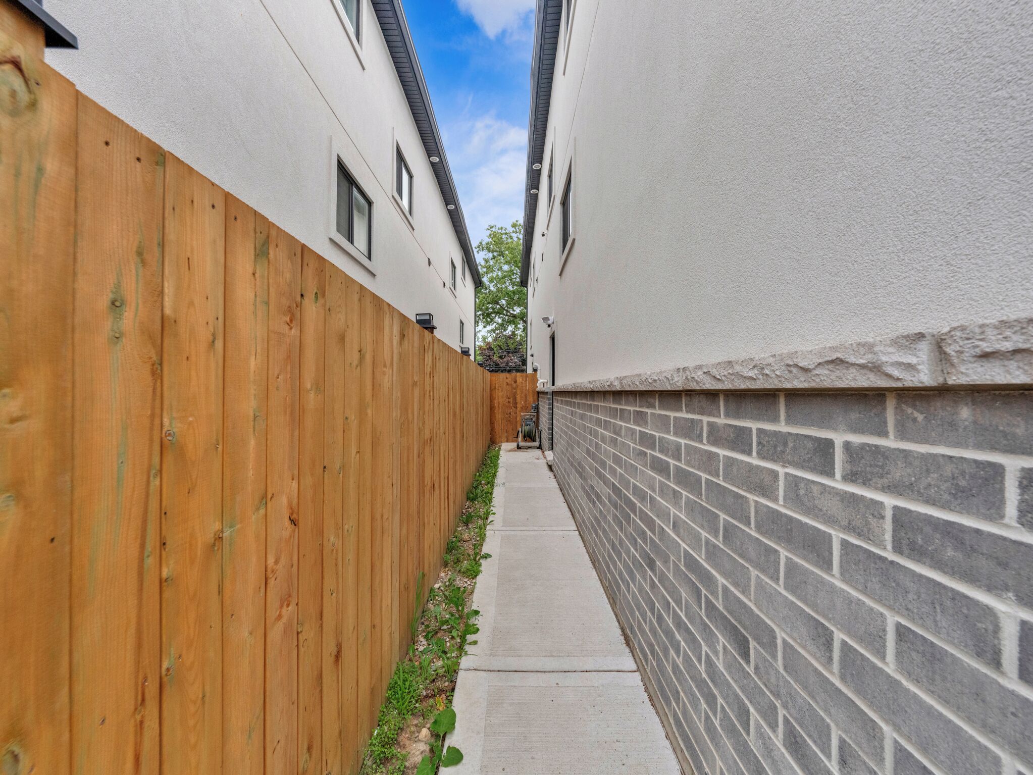 Un estrecho callejón entre dos edificios, con una cerca de madera en un lado y un muro de ladrillo en el otro.