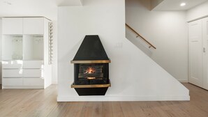 A modern interior with a built-in fireplace, a staircase, and a white wardrobe.